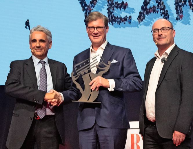 Gianluca Ventura (links) und Tom Terjesen übergeben Till Oberwörder, CEO Daimler Buses (Mitte) die COTY-Trophäe.