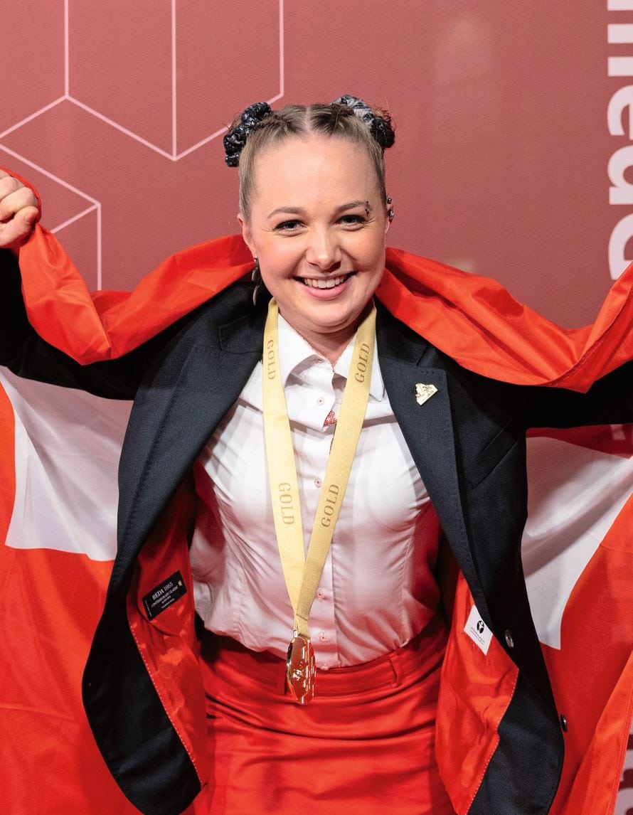 Nutzfahrzeug-Mechatronikerin Alina Knüsel feiert ihren Europameistertitel mit einer Goldmedaille bei den EuroSkills 2025 und der Schweizer Flagge.